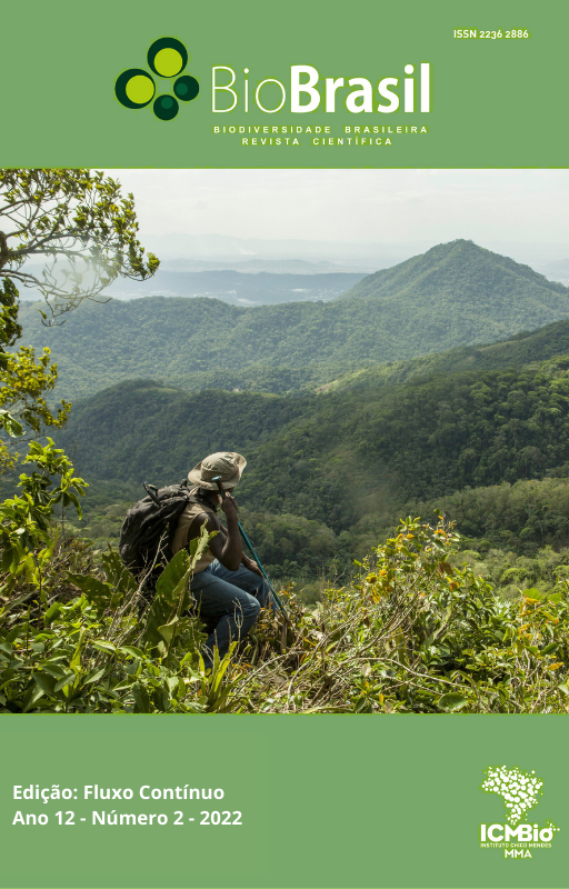 #paratodosverem:A capa da revista tem a cor verde na parte superior e na inferior. Na parte superior, traz a logomarca da revista BioBrasil. No meio da capa, há uma foto de paisagem com montanhas, onde, sentado em um morro, um homem descansa e aprecia as montanhas ao seu redor. Ele veste calça jeans, colete bege e camisa verde. Traz um chapéu em sua cabeça, também bege. Nas costas, uma mochila grande e na mão direita um bastão de caminhada. O céu está ensolarado e enevoado. A foto é de autoria de Rafael Duarte. Na parte de baixo da capa, à esquerda, está o título da edição (Fluxo Contínuo), seguido das informações: Ano 12, Número 2, 2022. Do lado oposto, à direita da página está a logomarca do Instituto Chico Mendes de Conservação da Biodiversidade (ICMBio).