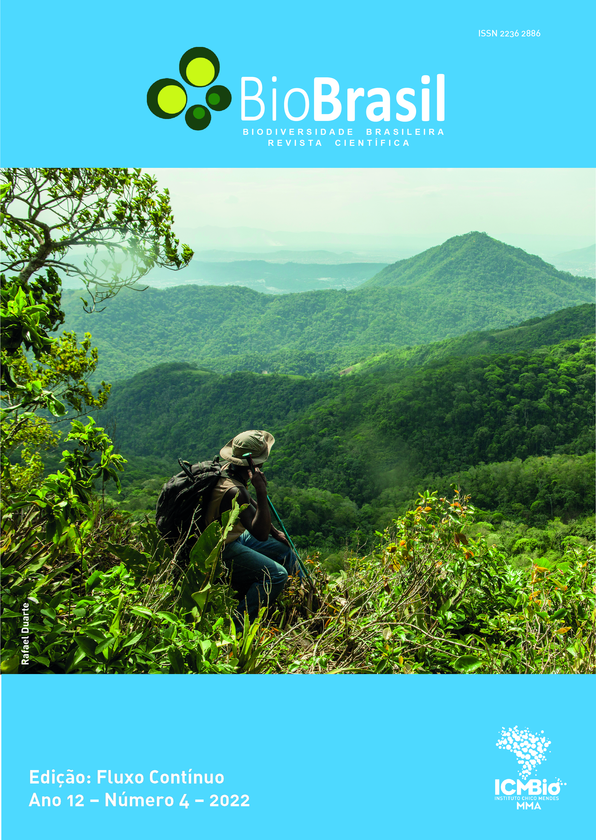 #paratodosverem:A capa da revista tem a cor azul turquesa na parte superior e na inferior. Na parte superior, traz a logomarca da revista BioBrasil. No meio da capa, há uma foto de paisagem com montanhas, onde, sentado em um morro, um homem descansa e aprecia as montanhas ao seu redor. Ele veste calça jeans, colete bege e camisa verde. Traz um chapéu em sua cabeça, também bege. Nas costas, uma mochila grande e na mão direita um bastão de caminhada. O céu está ensolarado e enevoado. A foto é de autoria de Rafael Duarte. Na parte de baixo da capa, à esquerda, está o título da edição (Fluxo Contínuo), seguido das informações: Ano 12, Número 4, 2022. Do lado oposto, à direita da página está a logomarca do Instituto Chico Mendes de Conservação da Biodiversidade (ICMBio).